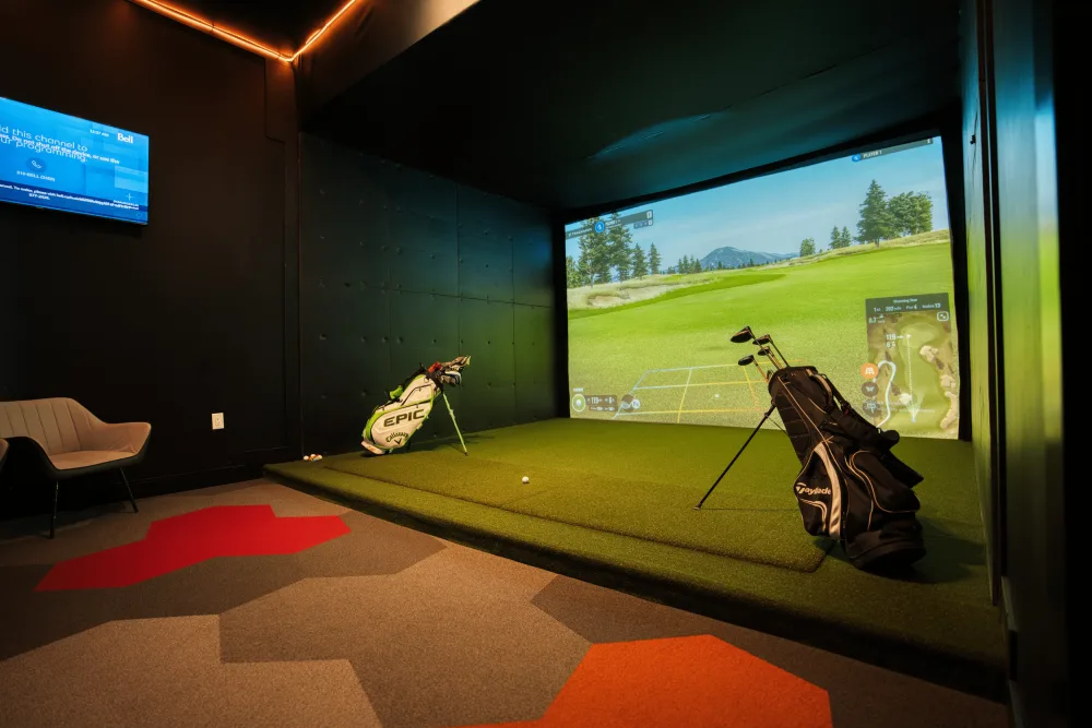 A private Swing Zone simulator suite with a large golf screen, club bags, and lounge seating